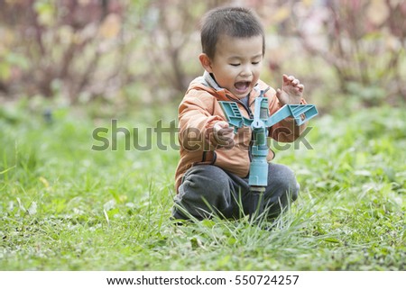 Happy Chinese baby boy playing a faucet in grass, shot in Beijing, China