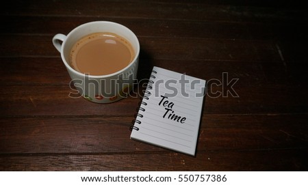 A cup of hot chocolate and a chocolate chip cookies isolated on a rustic wooden background. A simple message write on the notebook to make your day.