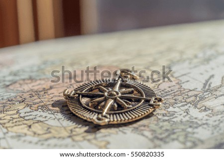 Closeup of vintage compass on old world map in front of heavy curtains, travel background with space for text
