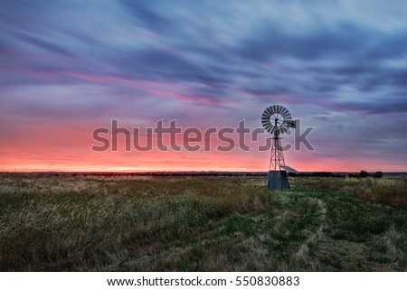 Beautiful sunset falling behind a windmill. Royalty-Free Stock Photo #550830883