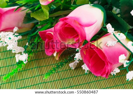 Pink fabric roses on bamboo background, closeup picture.