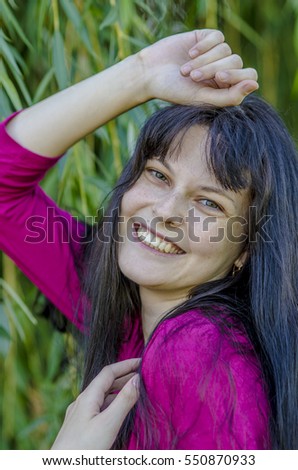 Young brunette girl with freckles in red dress in the summer garden