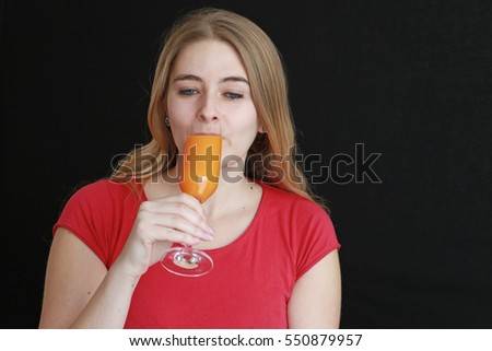 A young woman drinks a glass of orange juice.