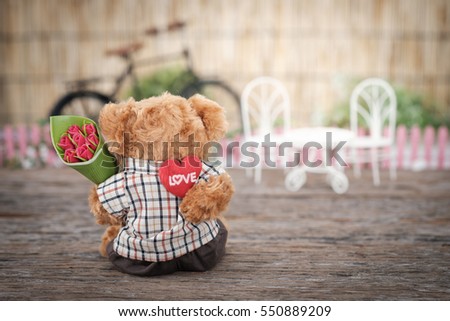 Teddy Bear holding a heart-shape pillow and bouquet of roses in valentine concept with space for write, AF point selection and blur, Vintage tone picture.