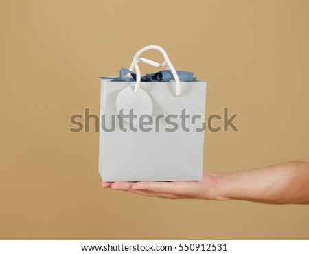Blank blue paper gift bag mock up holding in hand. Empty plastic package mockup hold in hands isolated. Consumer pack ready for logo design or identity presentation. Product packet handle