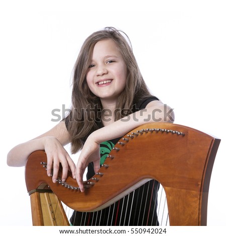 young girl in black shirt leans on harp in studio against white background and smiles