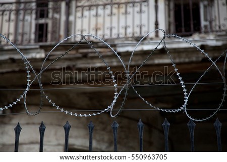 wire fences and railings in front of a old blurry house