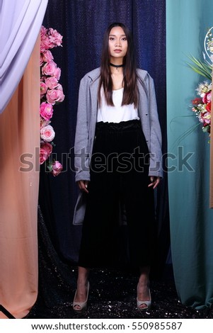 Asia Woman long straight hair white shirt black pants gray coat stand fashion pose on Pink Rose flower in bouquet with old rose color chiffon curtain fabric as background