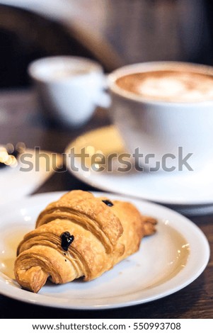 Delicious croissant and coffee. Breakfast with Coffee cup and fresh baked croissants on wooden background. Vintage effect style pictures. Selective focus. Shallow depth of field.