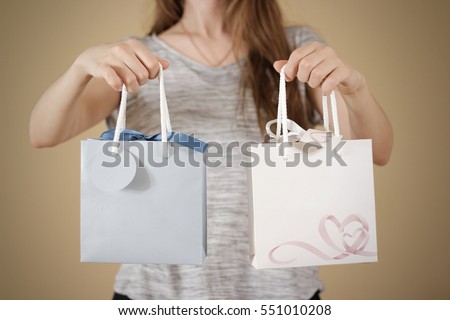 Girl holding in hand blank two paper gift bag with hearts mock up. Empty package mockup hold in hands isolated. Consumer pack ready for logo design or identity presentation. Product packet handle