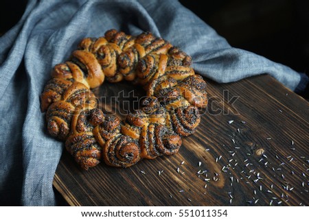 Bun with poppy seeds, Bagel on a wooden board with gray linen napkin on a black background