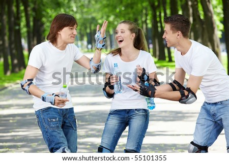 Young laughing people on rollers in park
