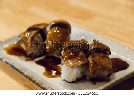 Natural lighting and shadow of blur foie gras sushi served in white plate on dining table of Japanese restaurant in Bangkok, Thailand.