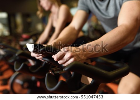 Close-up of hands of a man biking in the gym, exercising legs doing cardio workout cycling bikes. Couple in a spinning class wearing sportswear. Royalty-Free Stock Photo #551047453