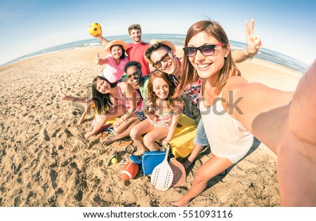 Group of multiracial happy friends taking selfie and having fun with beach sport games - Summer joy concept and multi ethnic friendship - Sunny afternoon color tones with focus on girl holding camera