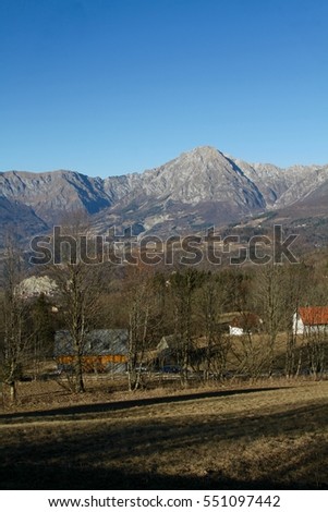 Alpago, italian Dolomites: mountains, fields and trees on a sunny winter day