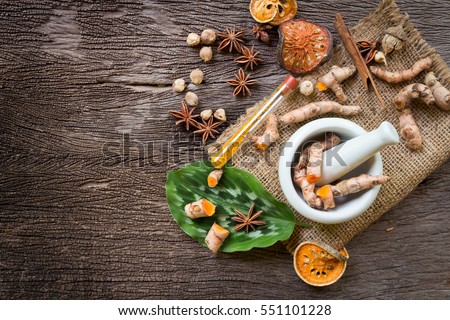 Turmeric in Mortar Grinder drugs and ingredient herbs on wooden background Royalty-Free Stock Photo #551101228