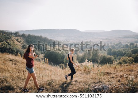 Beautiful young girls walk on autumn mountain slopes, fun, jump. female friendship