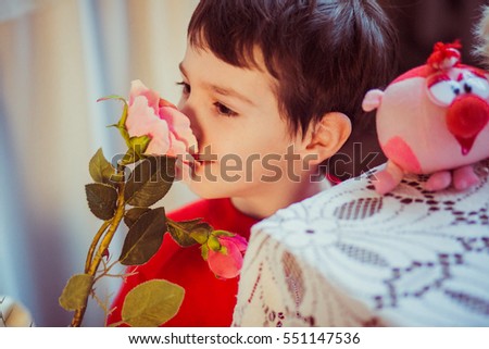 A portrait of a boy smiling and smelling a rose