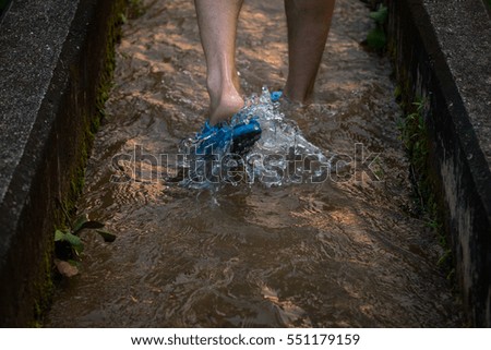 A guy walking through a puddle outdoors during sunset