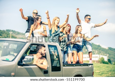 Group of friends driving on the back of pick-up car and having fun - People on vacation and enjoying an excursion in the nature
