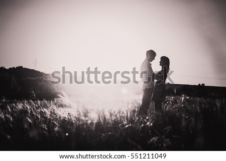 Black white photography romantic couple standing  and kissing on background summer meadow sunset