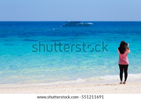 Tourist woman taking photo with camera  on the beach
