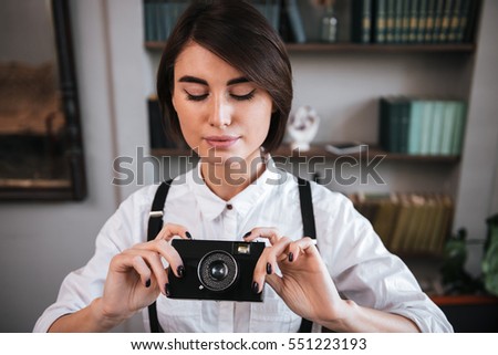 Attractive Authoress in white shirt making photo on retro camera