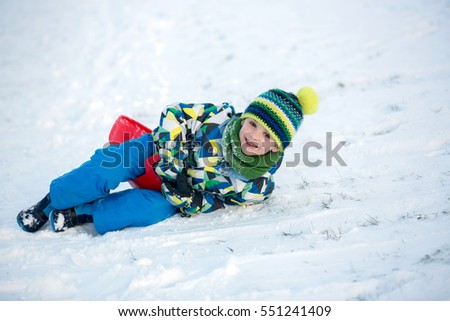 Cute child, boy, sliding with bob in the snow, wintertime, happiness concept