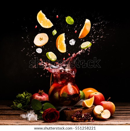 Sangria. Flying fruits. Apple, orange, lime, pomegranate, mint. Drink. Wine. Concept. Dark moody. Spain. Beverage jug. Juice jar. Royalty-Free Stock Photo #551258221