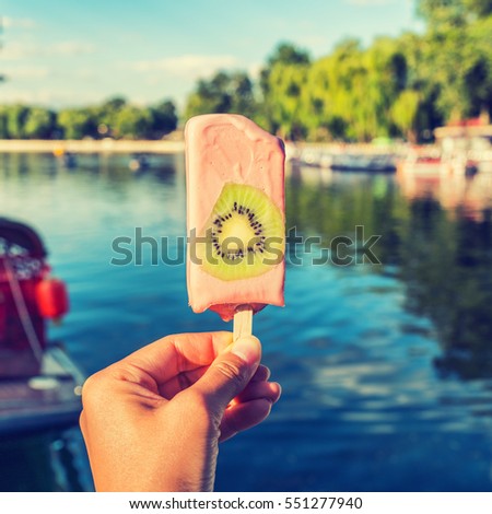 Food selfie girl holding ice pop in summer park. Filtered for smartphone app style sharing on social media.