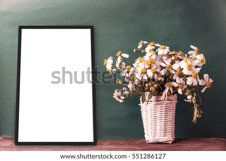 blank black frames on old green wall with chamomile flower in basket vintage style