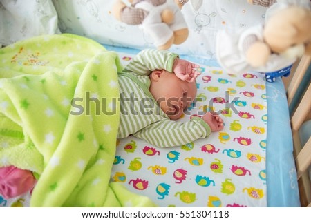 A newborn infant sleeping in his bed.
