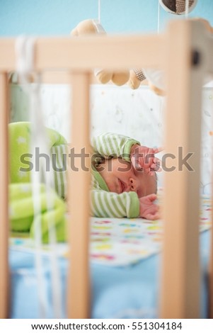 A newborn infant sleeping in his bed.