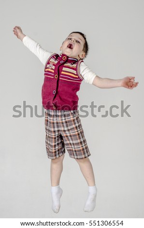 Little baby boy in plaid shorts and vest jumps