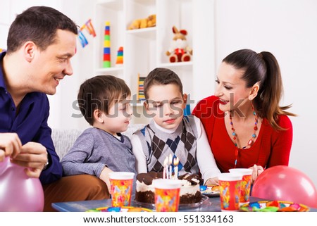 Family celebrating birthday - young boy blowing out candles on cake.