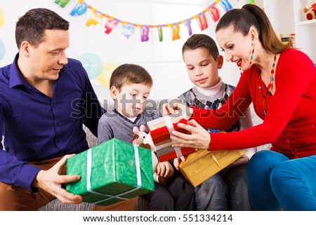Family celebrating a birthday opening gifts in living room. 