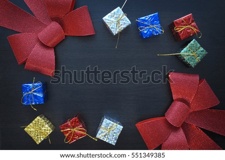 Colorful gift box and red bow on black wood table background 