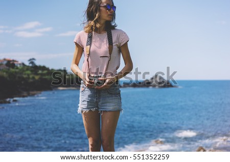 Tourist traveler photographer making pictures seascape on vintage photo camera on background piar, hipster girl enjoying peak mountain and nature holiday, mockup ocean waves view, blurred backdrop