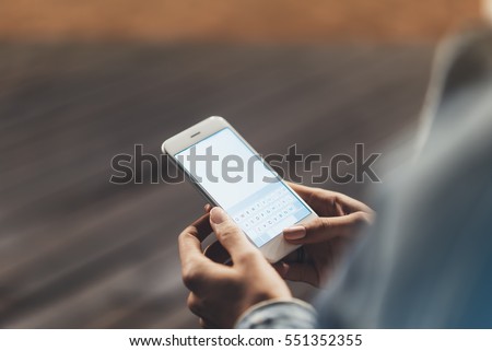 Girl pointing finger on screen smartphone on background wooden floor in night atmospheric city, hipster using in female hands and texting mobile phone, mockup glitter street lifestyle, blured backdrop Royalty-Free Stock Photo #551352355