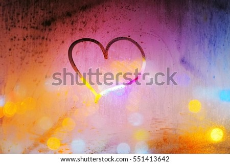 Abstract background - heart painted on a misted window on the background of colorful city lights at night