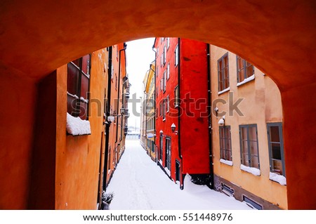 View of narrow street and colourful buildings in Gamla Stan. The Old Town in Stockholm, Sweden. Winter season and cloudy day Royalty-Free Stock Photo #551448976