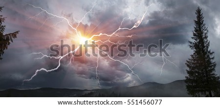 Scary clouds scenic natural phenomena in a cloud of black and white shades and dazzling colors - clouds after rain and bad weather in the storm with lightning over the mountains Royalty-Free Stock Photo #551456077