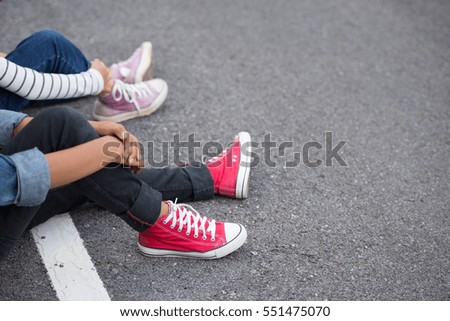 Legs of young travelers on a road in the woods.