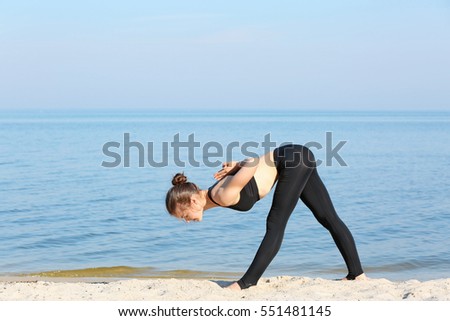 Attractive young woman doing yoga by the sea
