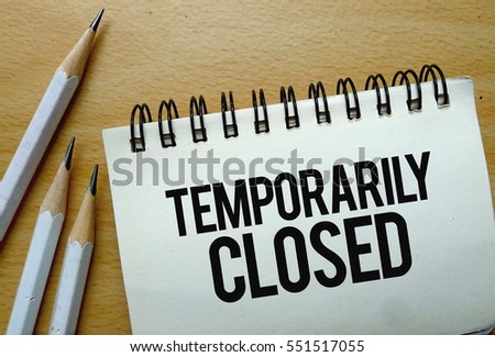 Temporarily Closed text written on a notebook with pencils Royalty-Free Stock Photo #551517055