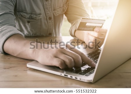 Online payment,Man's hands holding a credit card and using laptop on wood desk for online shopping.