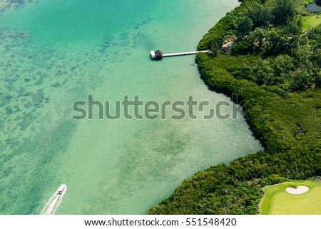 Aerial picture of Mauritius Island. Aerial view of golf course and lagoon of Mauritius. Speedboat heading to a small pier