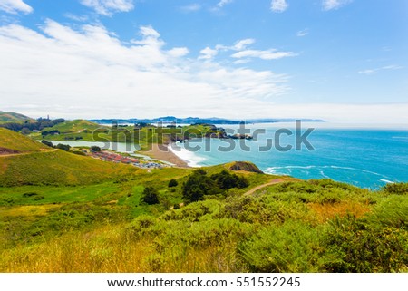 San Francisco in distant background seen from atop the Marin Headlands above Fort Cronkhite and Rodeo Beach along the coastal trail on a summer day in California. Horizontal Royalty-Free Stock Photo #551552245