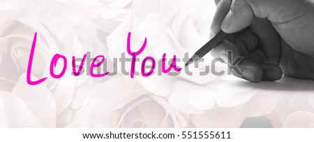 Hand holding a pencil on a vintage rose background, writing for word " Love You "